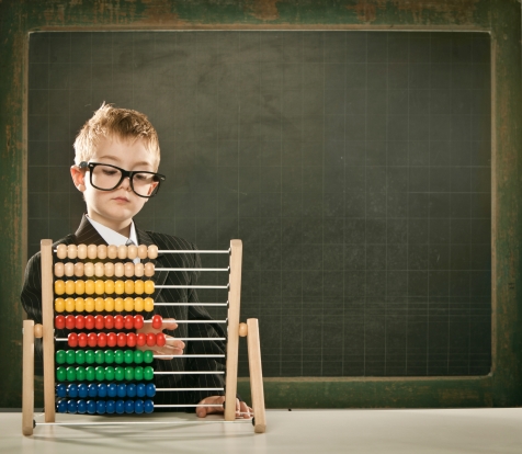 young serious scientist child with abacus and copyspace blackboa